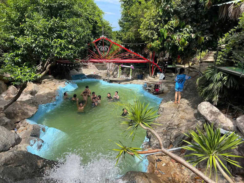 Hình ảnh du khách đang tận hưởng việc tắm mát tại Giếng Tiên, hồ nước trong xanh giữa lòng khu du lịch