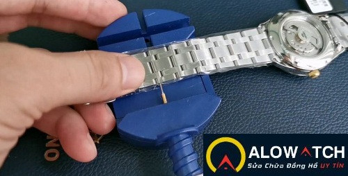 Đồng hồ dây kim loại đang được điều chỉnh, minh họa chi phí cắt mắt đồng hồ