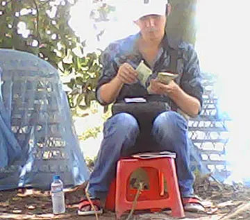 Hình ảnh một cá nhân đang thu tiền tại khu vực có nghi vấn hoạt động bồ gà c2, cho thấy hoạt động tài chính bất hợp pháp.