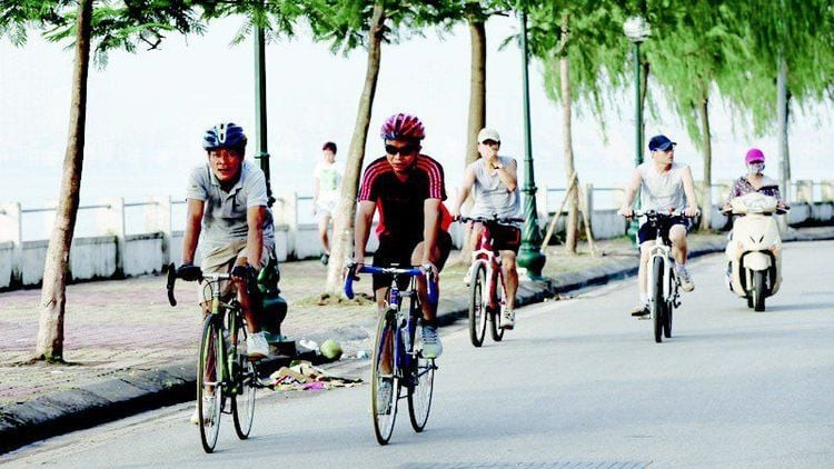 Người đàn ông đạp xe trên đường nhựa với khung cảnh thiên nhiên, thể hiện hoạt động thể dục ngoài trời